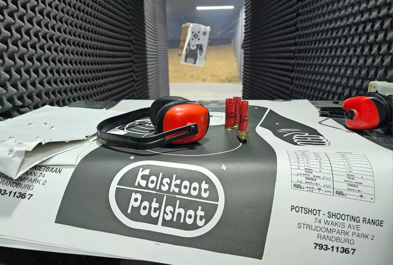Gun range supplies on a table, with a training target in the background