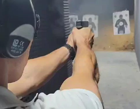 A close-up of a guy shooting a pistol at a shooting range