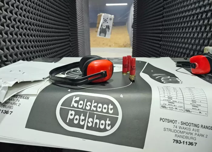 Gun range supplies on a table, with a training target in the background